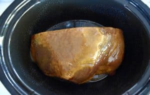 ham in a slow cooker with glaze on top.