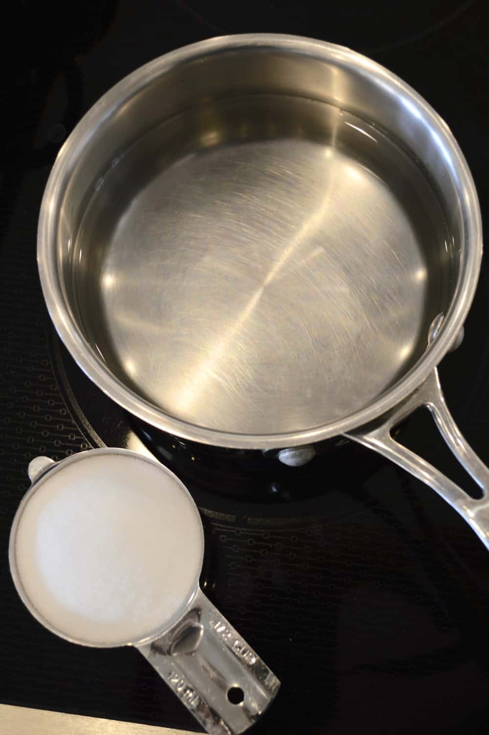 pan of water on a stove with a cup of salt next to it