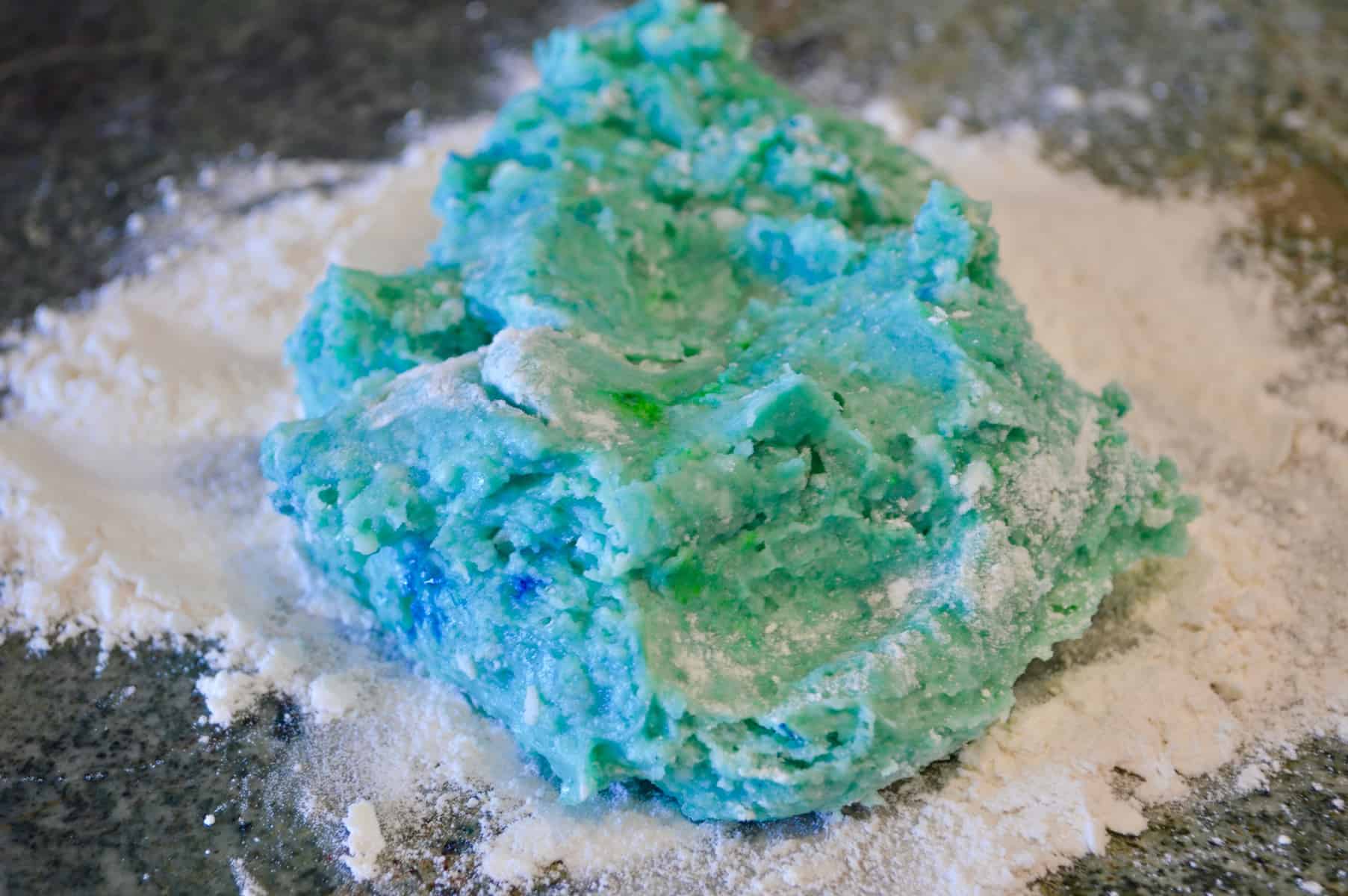 teal play doh on flour on a countertop 