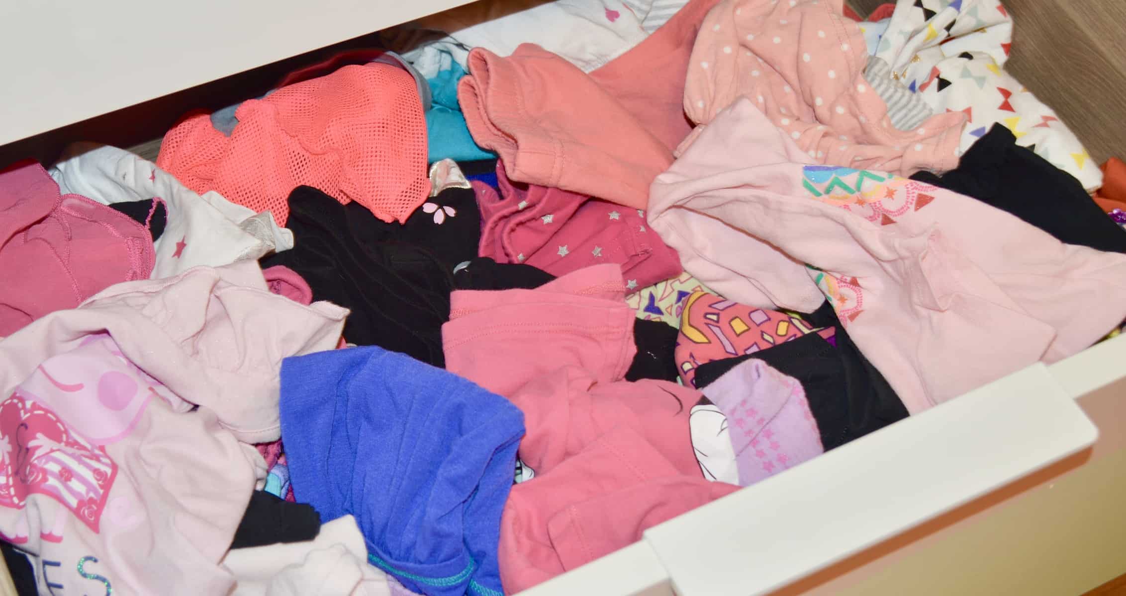 A drawer of messy unorganized girls clothes 