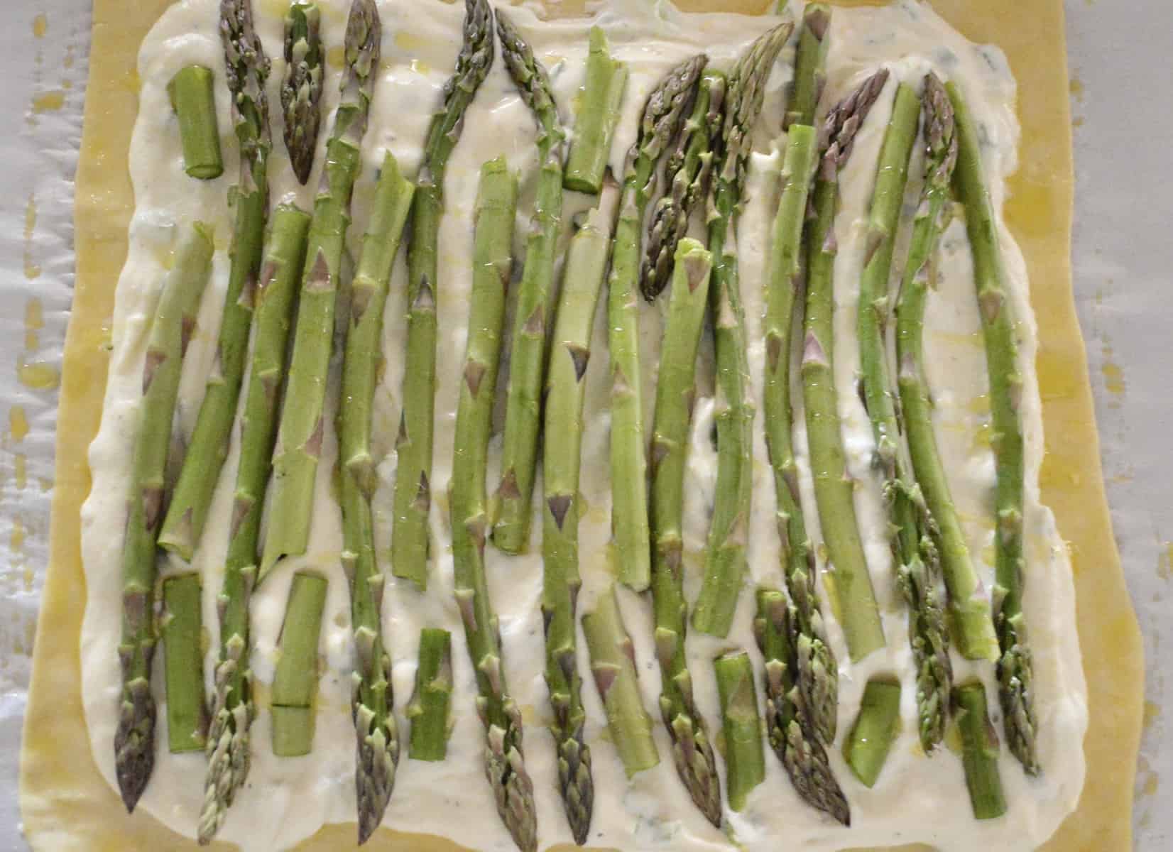 Puff pastry with ricotta spread and asparagus on top of parchment paper 