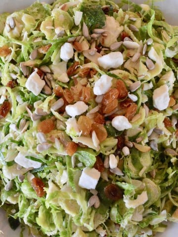 Brussels sprouts Salad with feta raisins and sunflower seeds in a white bowl