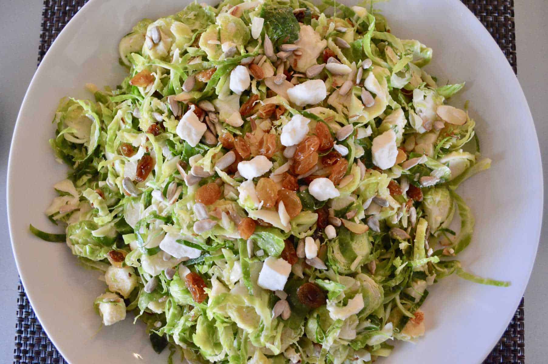 Brussels sprouts Salad with feta raisins and sunflower seeds in a white bowl