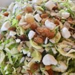 Brussels sprouts Salad with feta raisins and almonds in white bowl