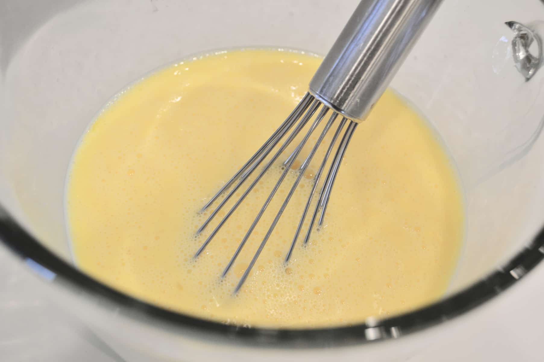 eggs beaten in a glass bowl with a whisk 