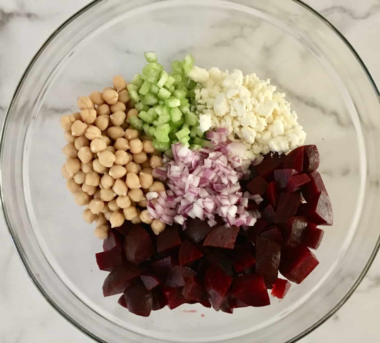 beets, feta, garbanzo, red onion, and celery in a glass mixing bowl. 