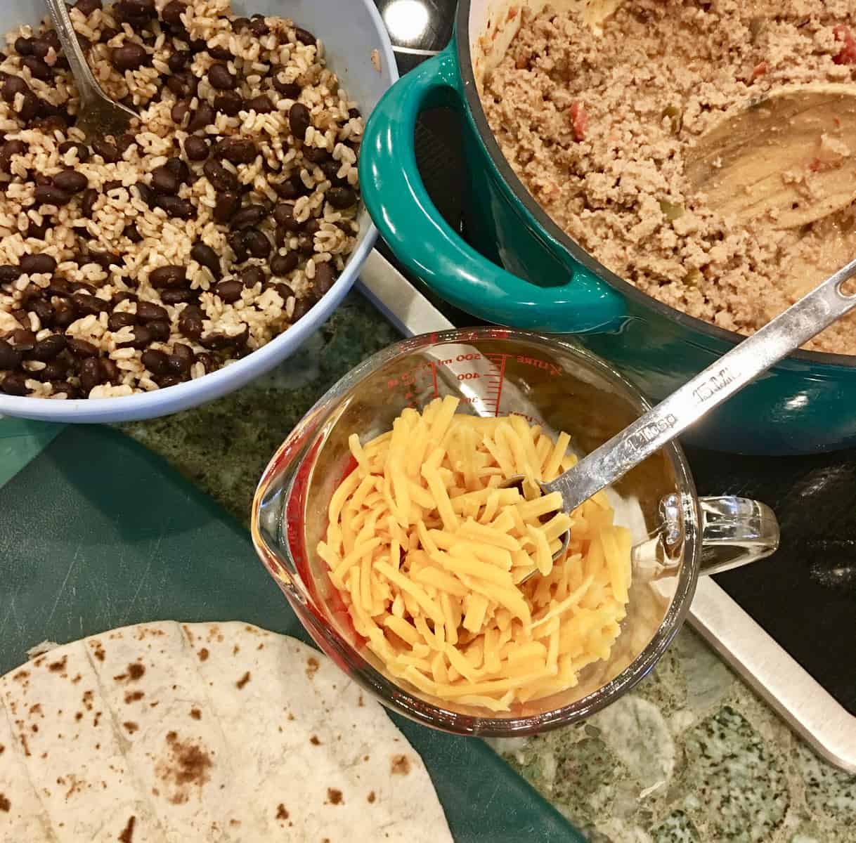 laying out cheese, turkey, and beans to fill the tortillas. 