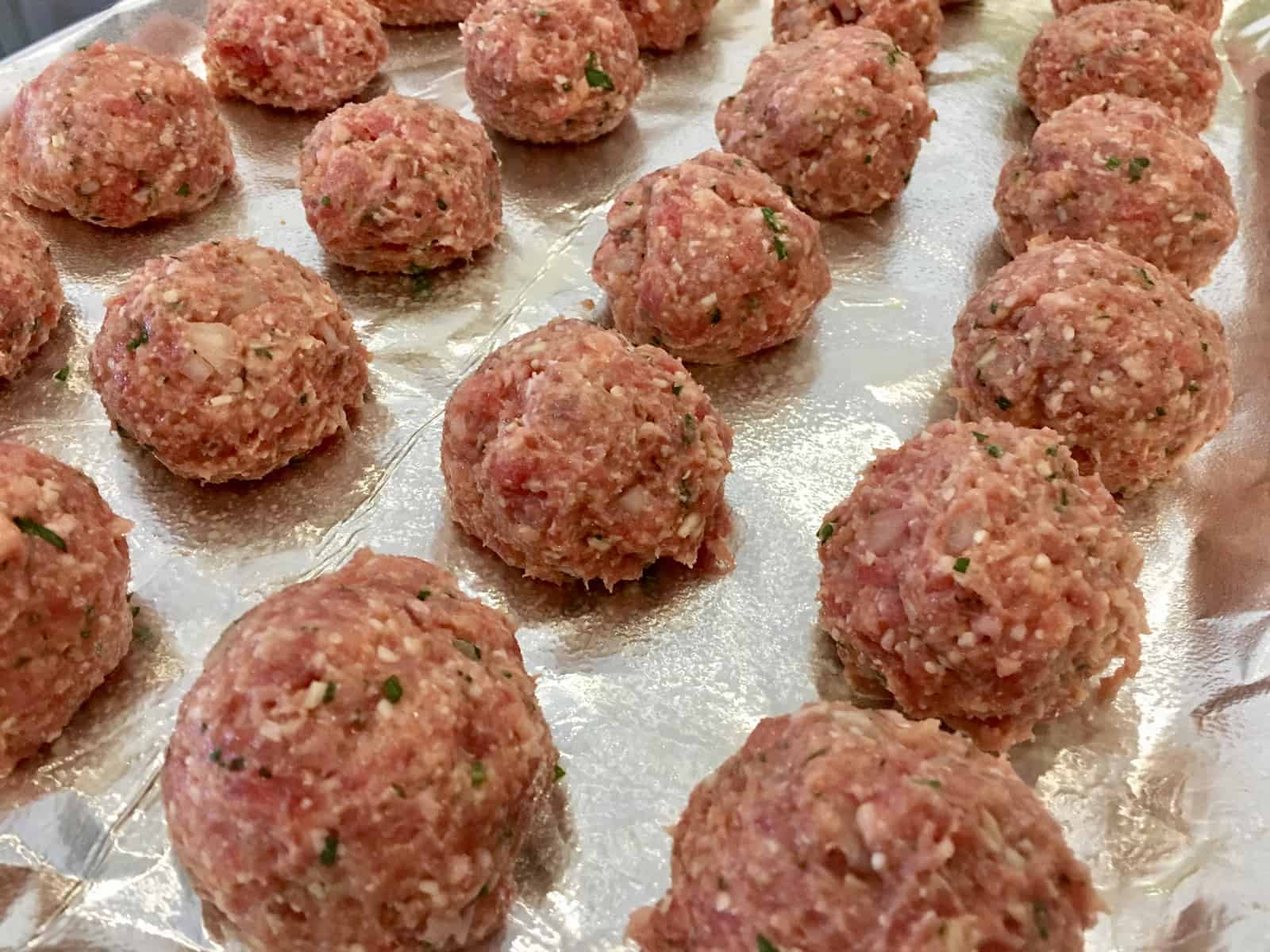 raw balls on a foil lined baking sheet. 