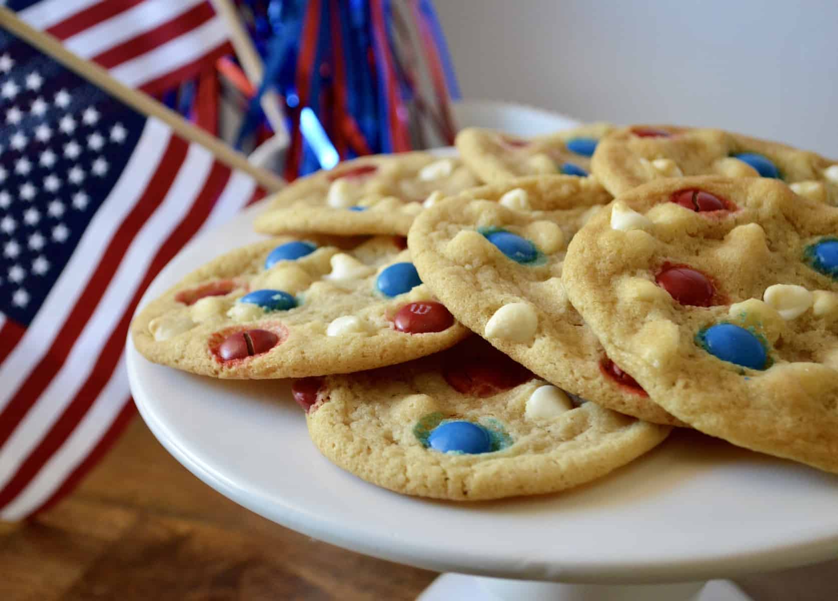 4th of July Cookies with red white and blue m&m's sitting on a white pedestal 