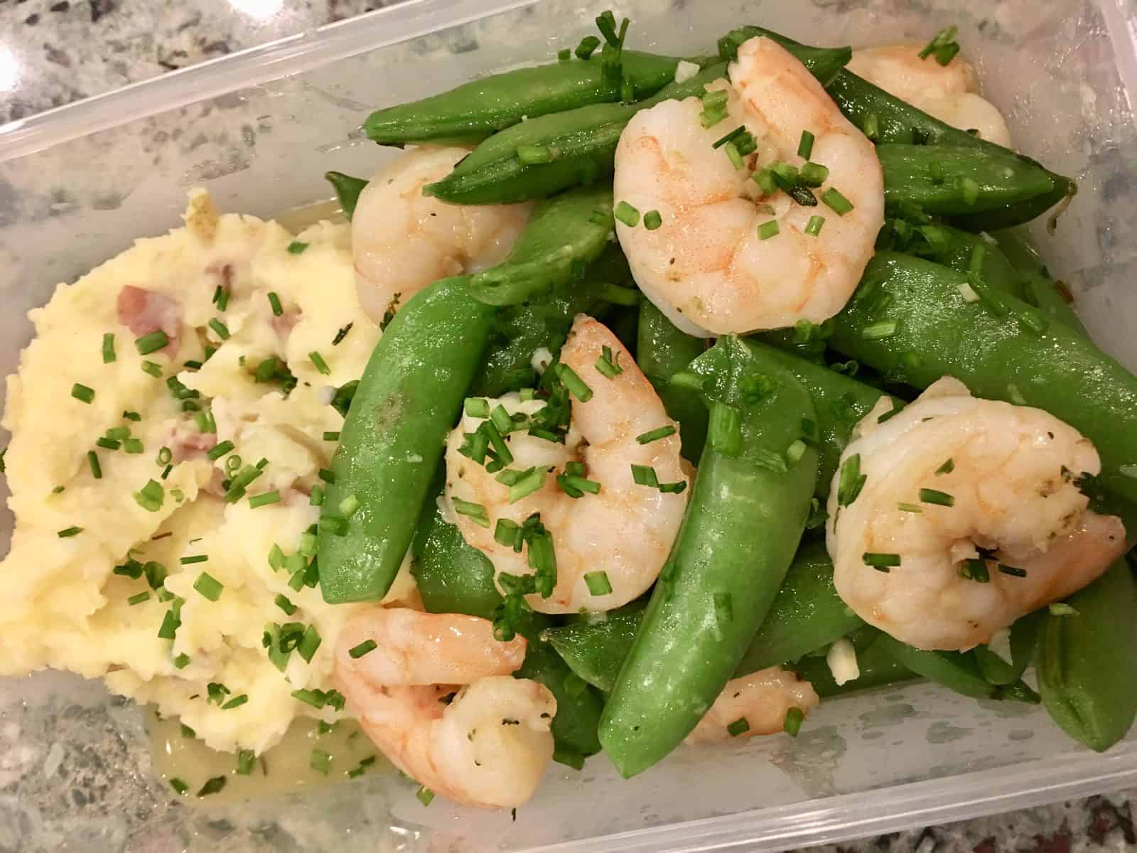 Garlic Shrimp, Snap Peas, and Mashed Potatoes in a meal prep container 