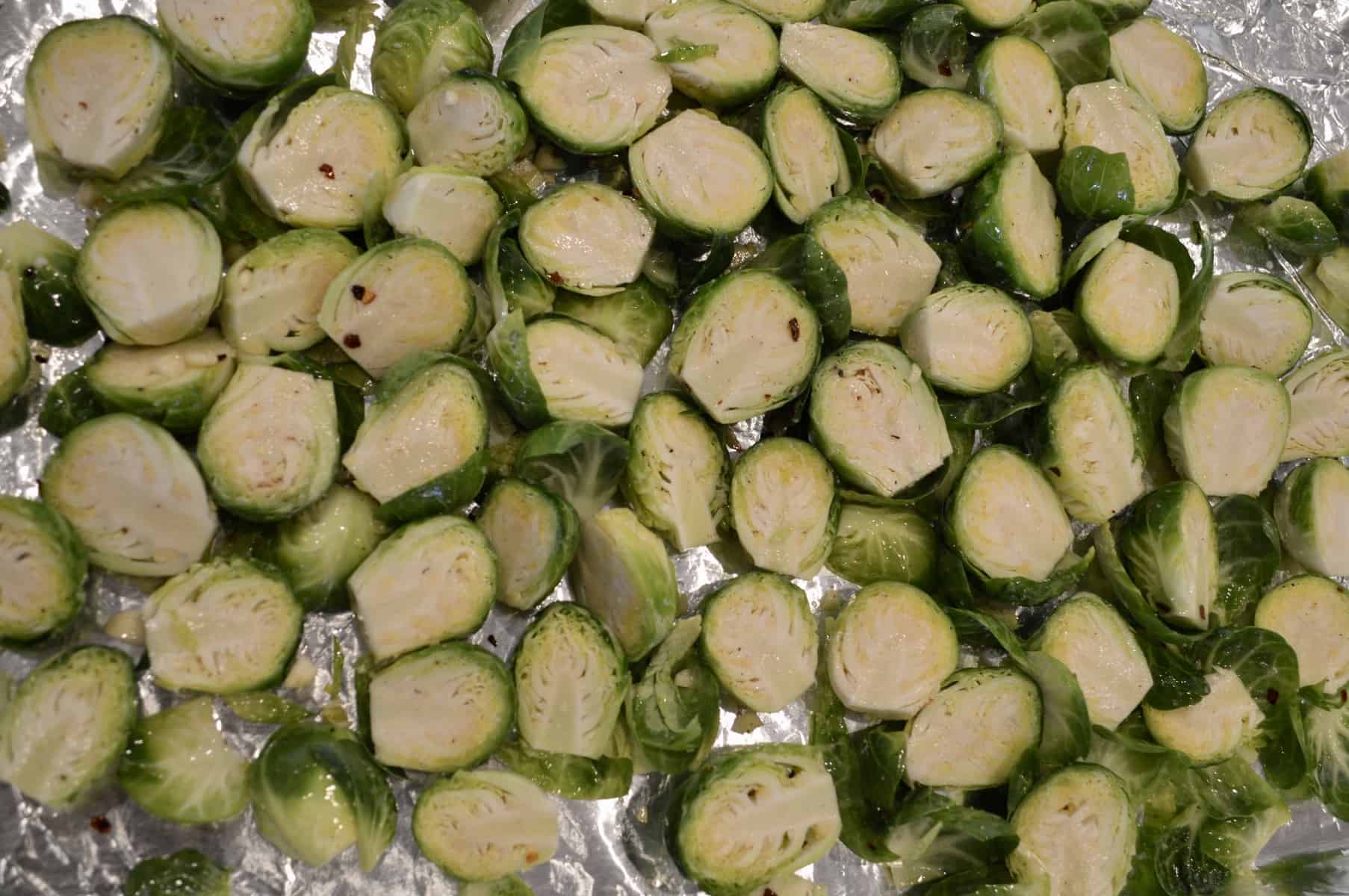 veggies cut in half on a foil lined baking sheet.