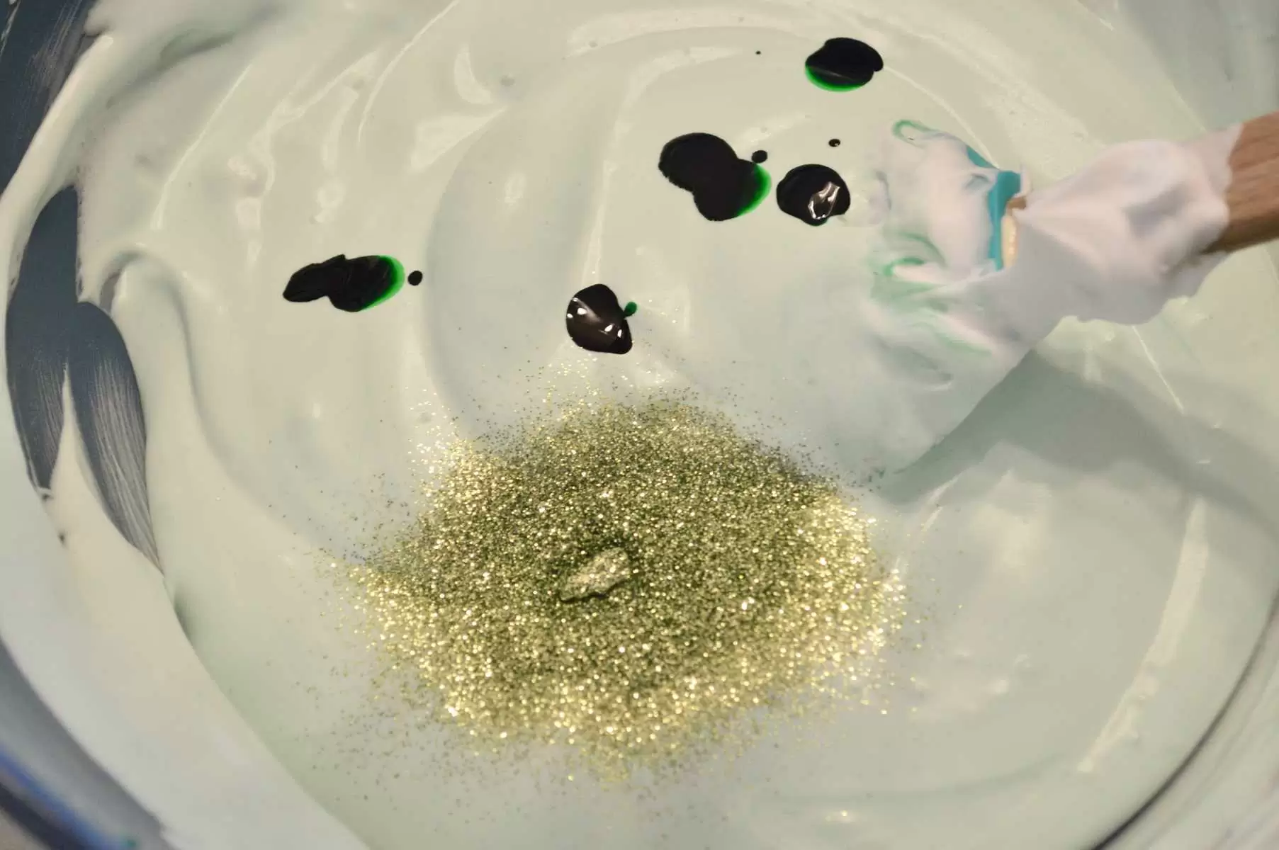 bowl of green colored batter with glitter and dye drops. 