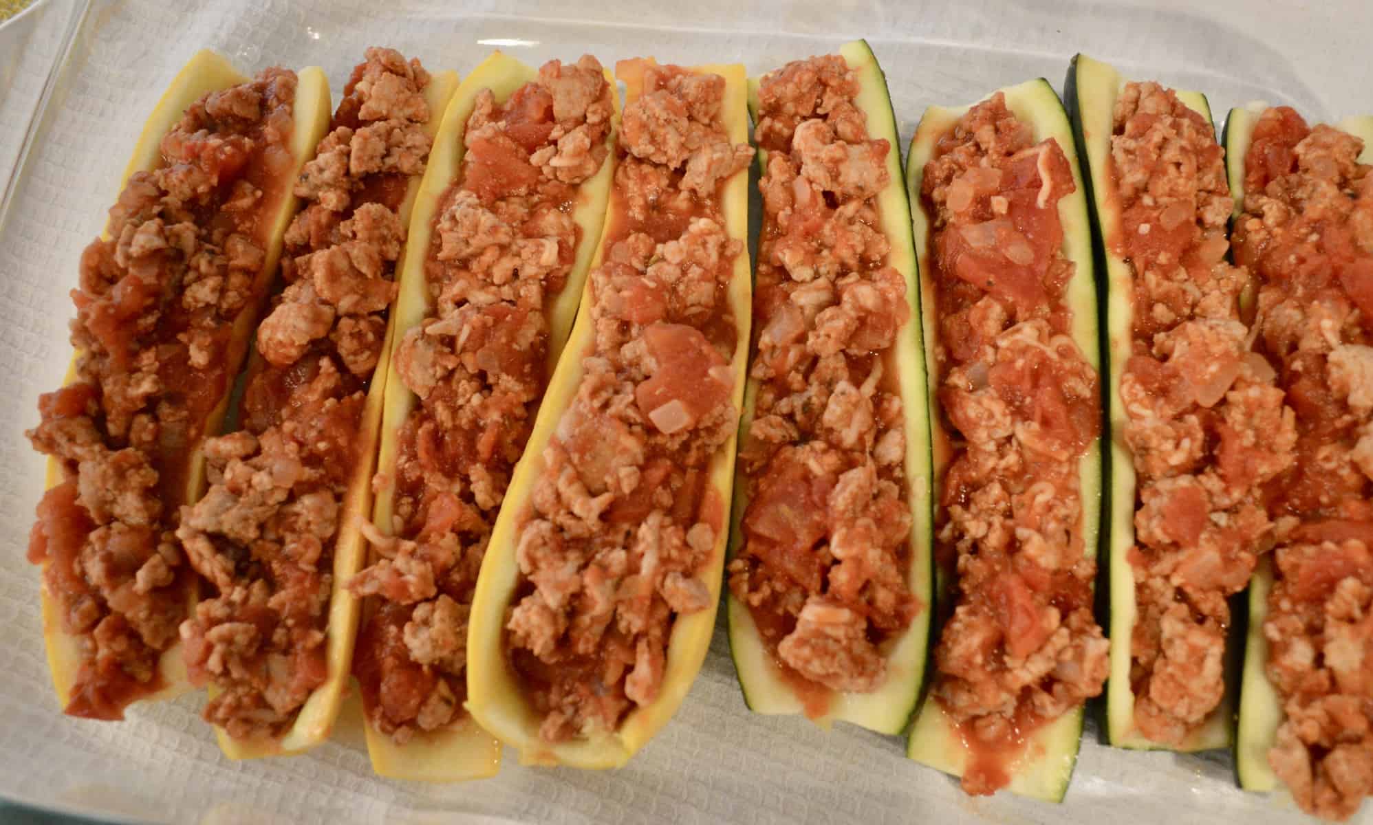 hollowed out squash filled with turkey meat in a glass baking pan. 