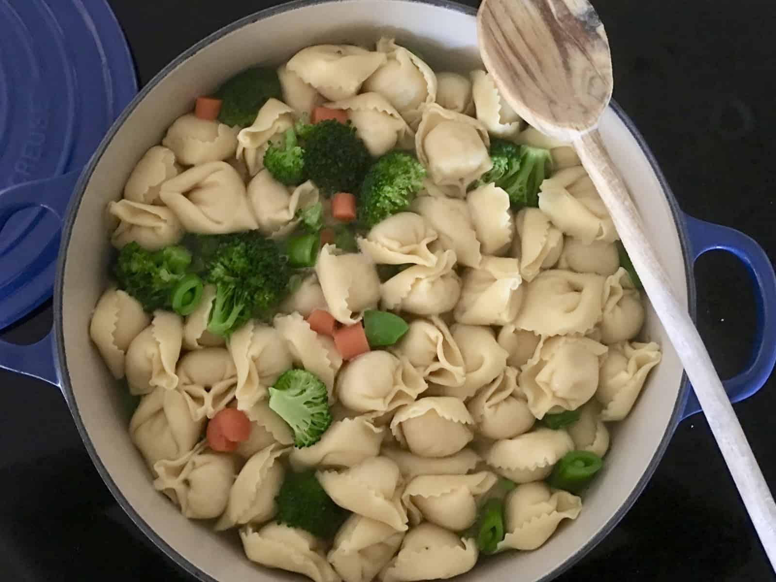 boiling pot of water with pasta and vegetables in it. 