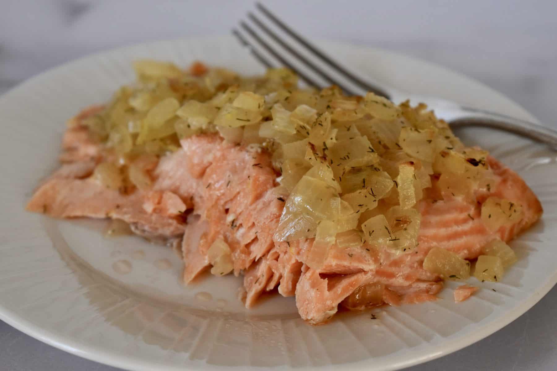 Salmon on a plate with caramelized onions on top. 