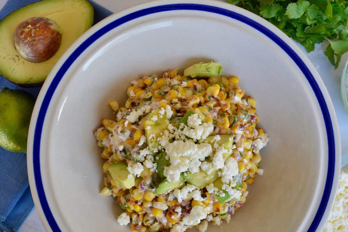 Mexican street corn salad with avocado in a white bowl. 