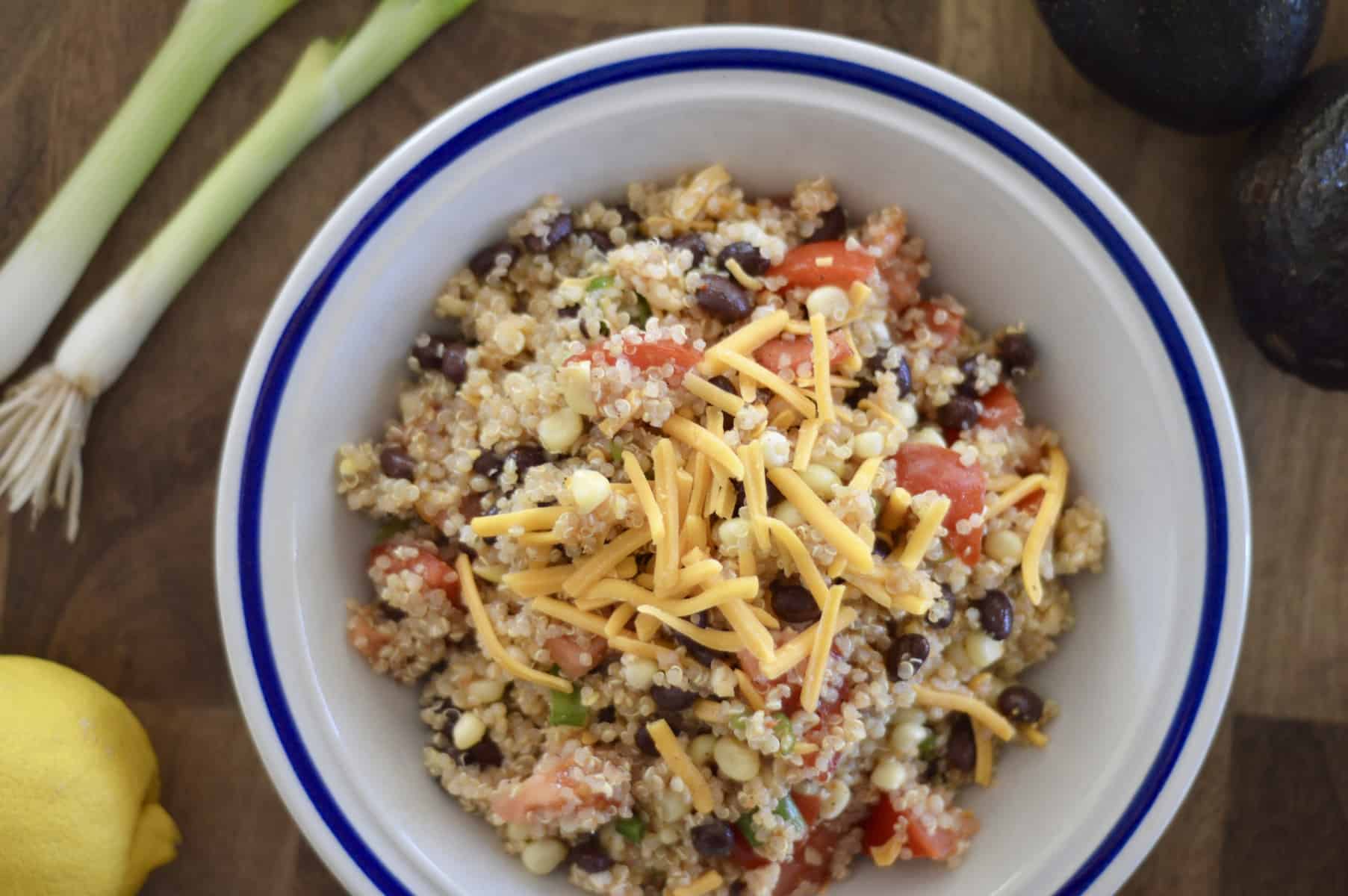 mexican quinoa salad on a wood board with lemon, avocado and green onion