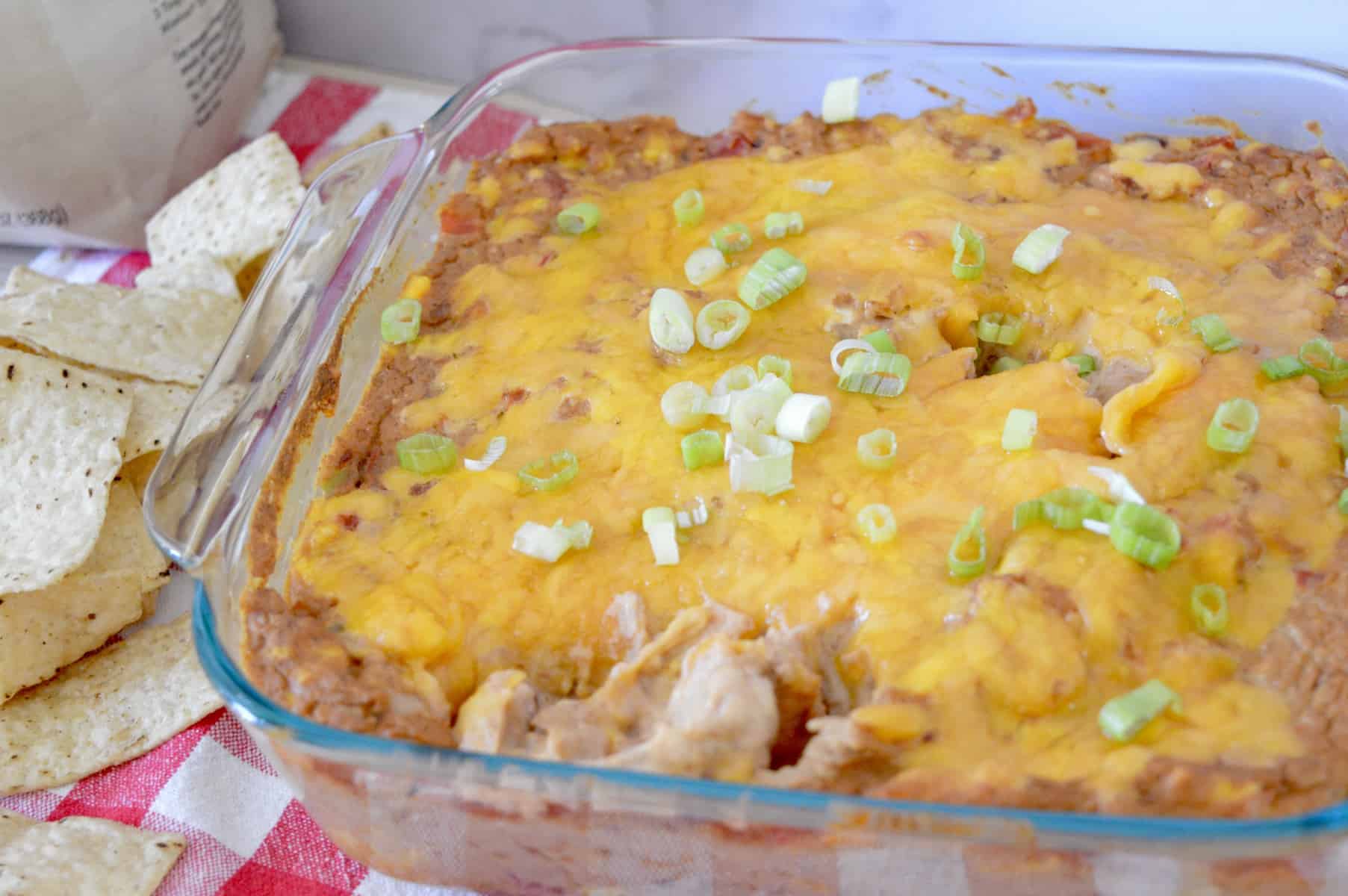 Cream Cheese Bean Dip in a glass pan with green onions on top. 