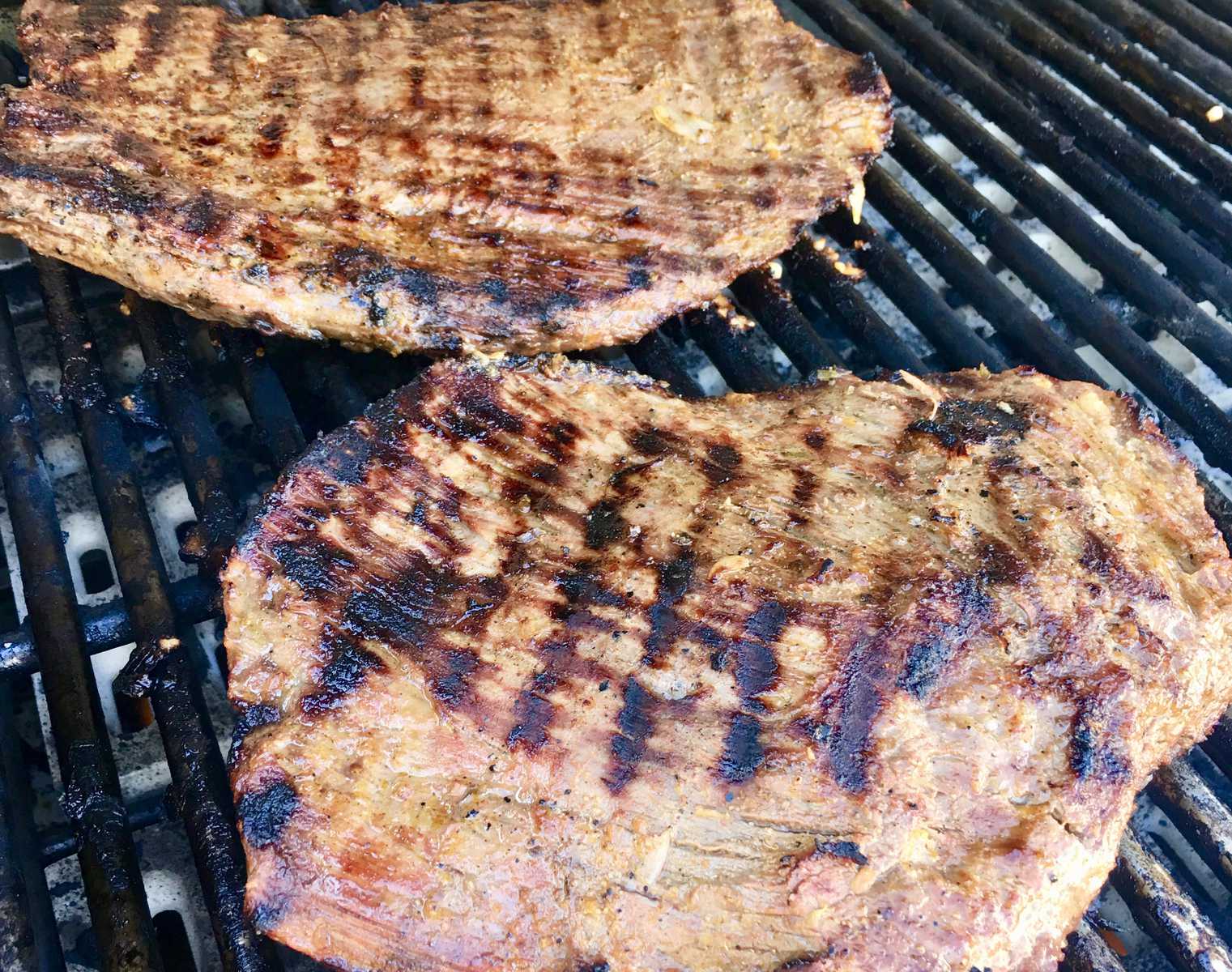 flank steak cooking on the grill. 
