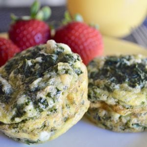 Spinach and Feta Egg Cups on a yellow plate with strawberries