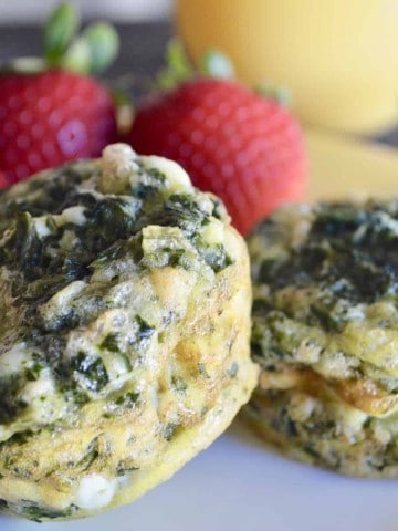 Spinach and Feta Egg Cups on a yellow plate with strawberries