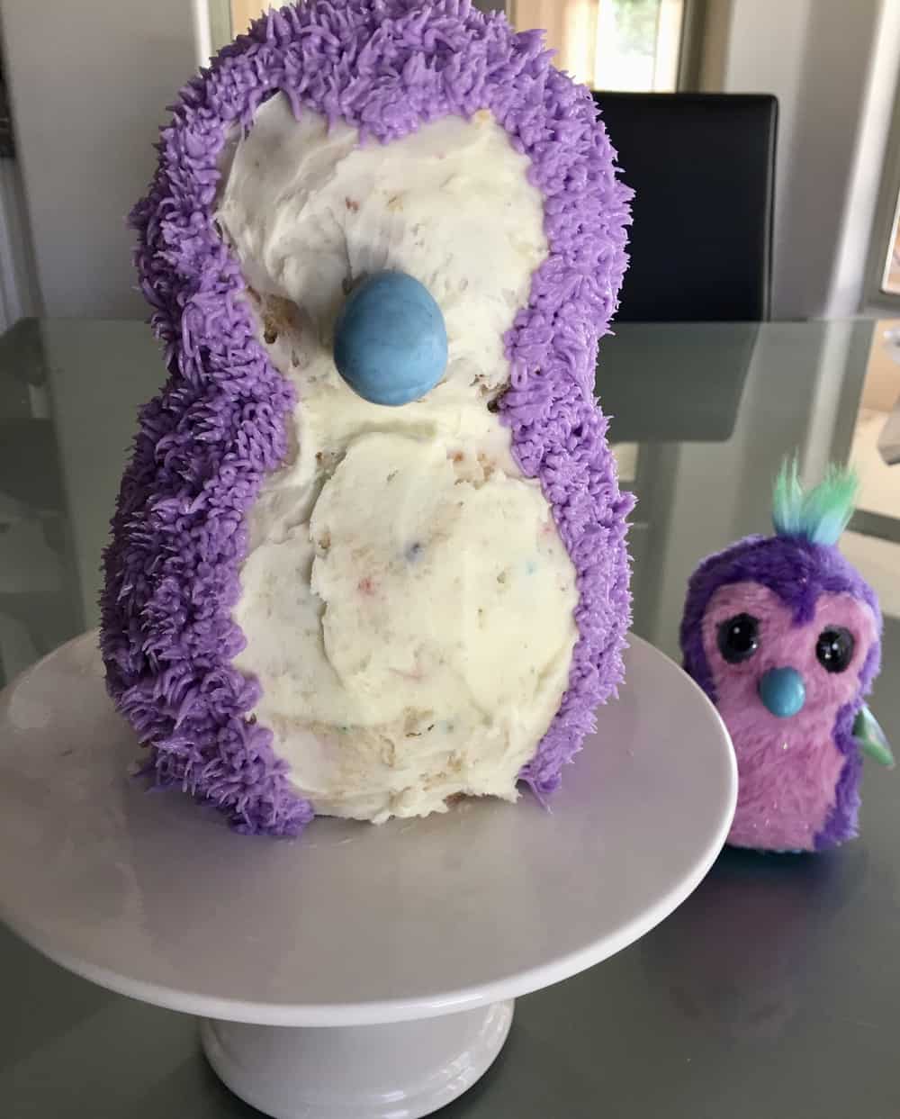 hatchimals cake on a white pedestal with purple frosting