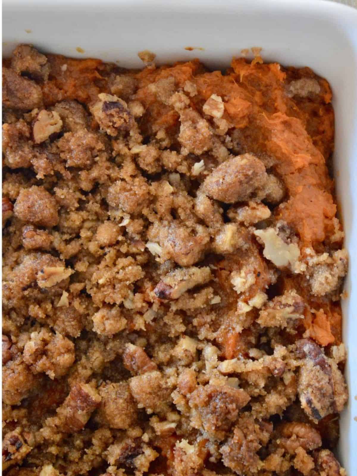 Sweet Potato Casserole with pecan streusel topping in a white serving dish. 