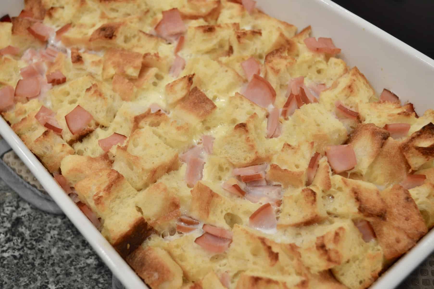 eggs benedict casserole just out of the oven in a white baking dish.