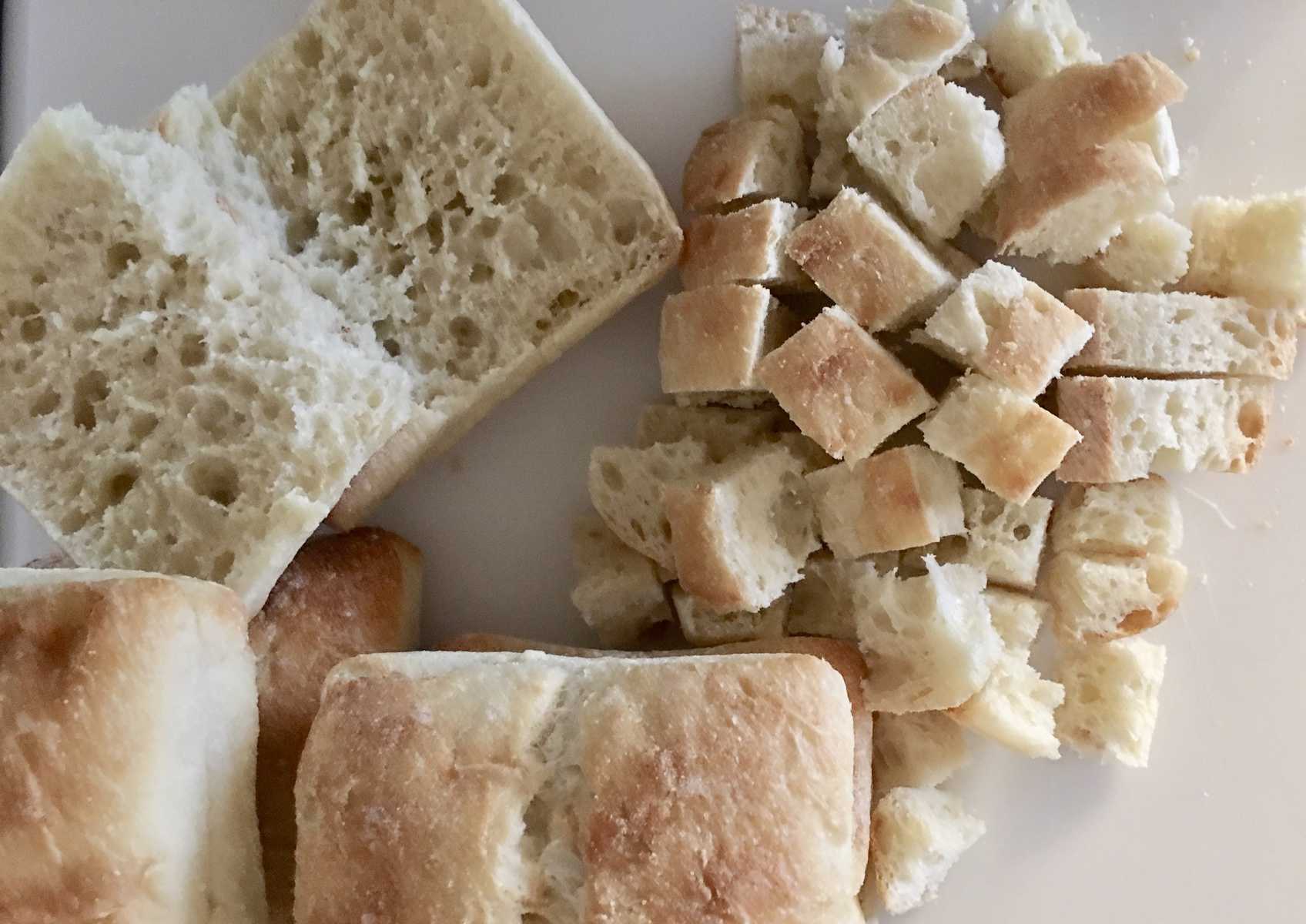 cutting up ciabatta rolls into cubes. 