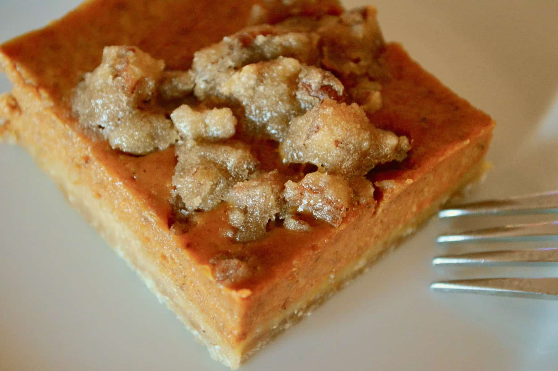 pumpkin pie bars on a white plate with a fork next to it. 