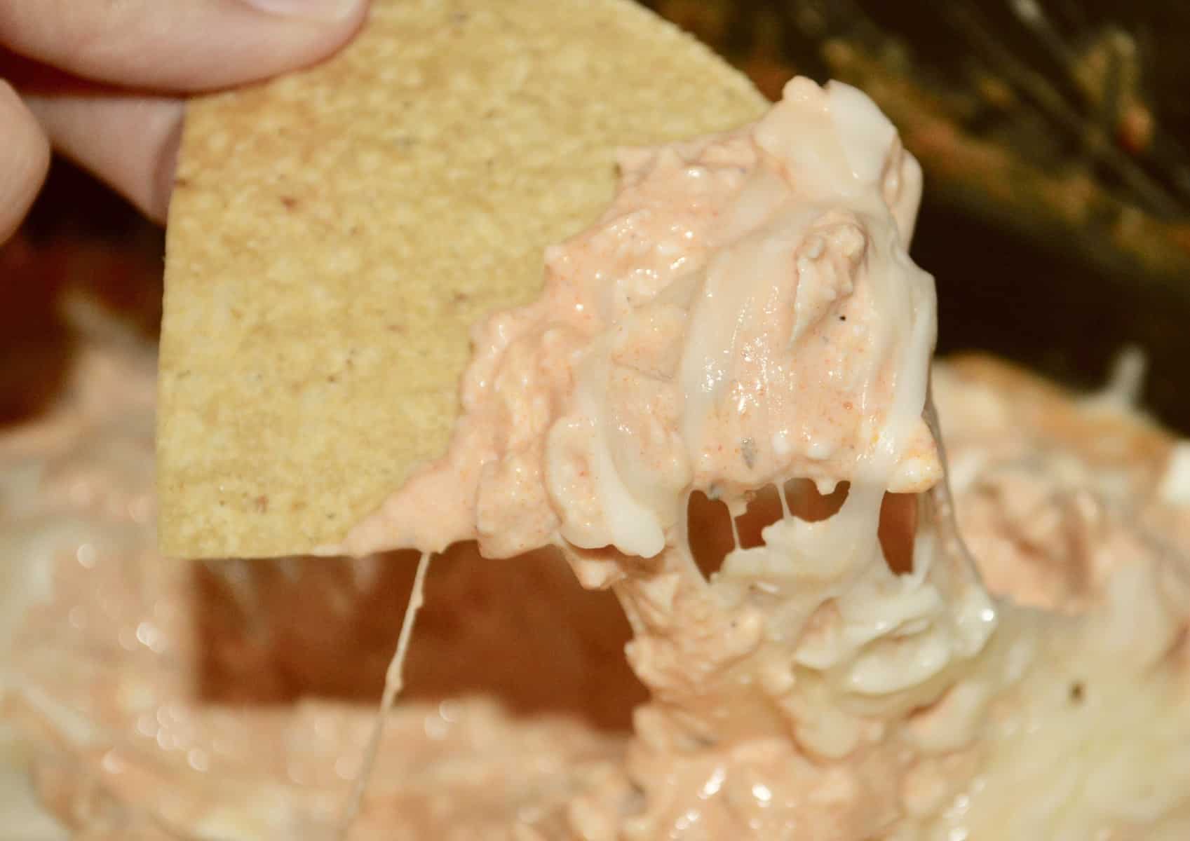 tortilla chip in a bowl of buffalo chicken dip in the crock pot 