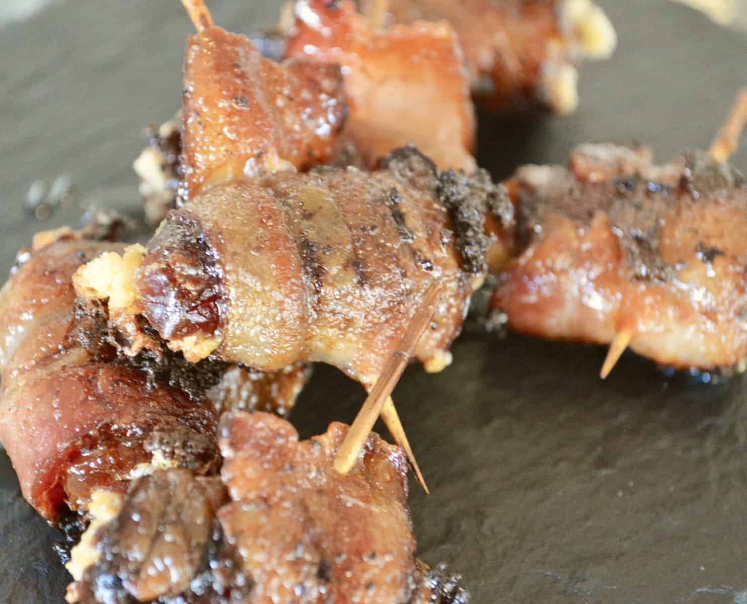Bacon Wrapped stuffed Dates on a black plate