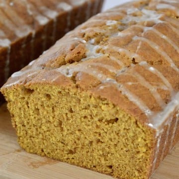 glazed pumpkin bread on a wood cutting board.