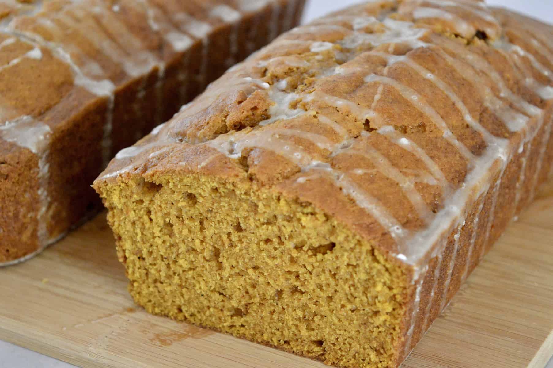 glazed pumpkin bread on a wood cutting board. 