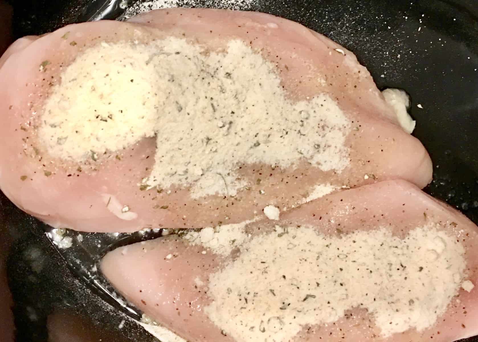 chicken breasts covered with ranch seasoning in a crock-pot.