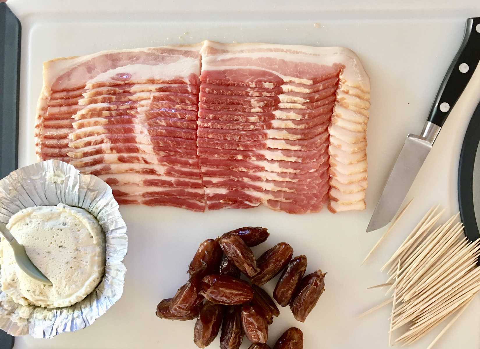 ingredients for bacon wrapped dates on a white cutting board