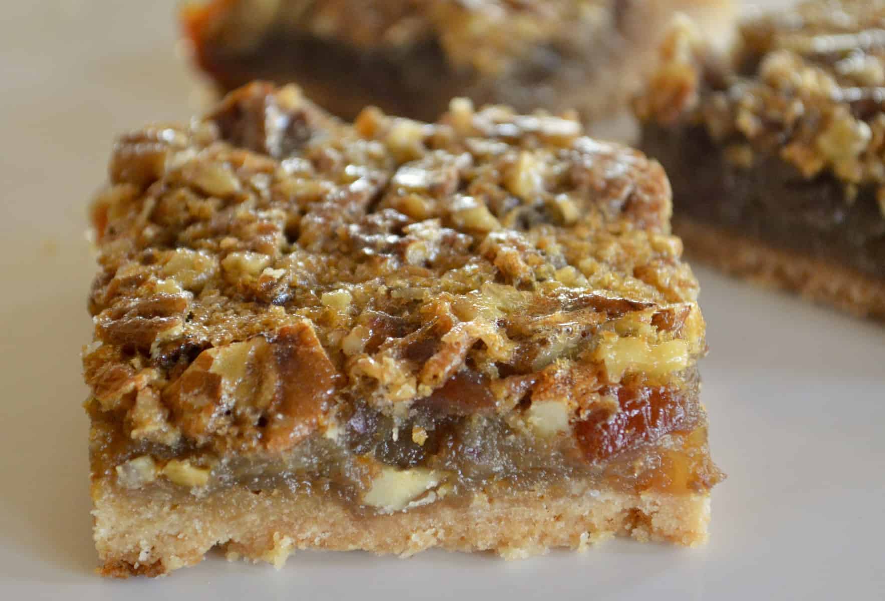 Pecan Pie Date Bars on a white plate with bars in the background 