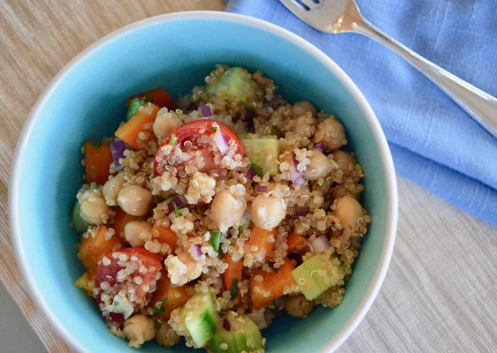 Easy Vegetable Quinoa Salad in a blue bowl with a fork and blue napkin