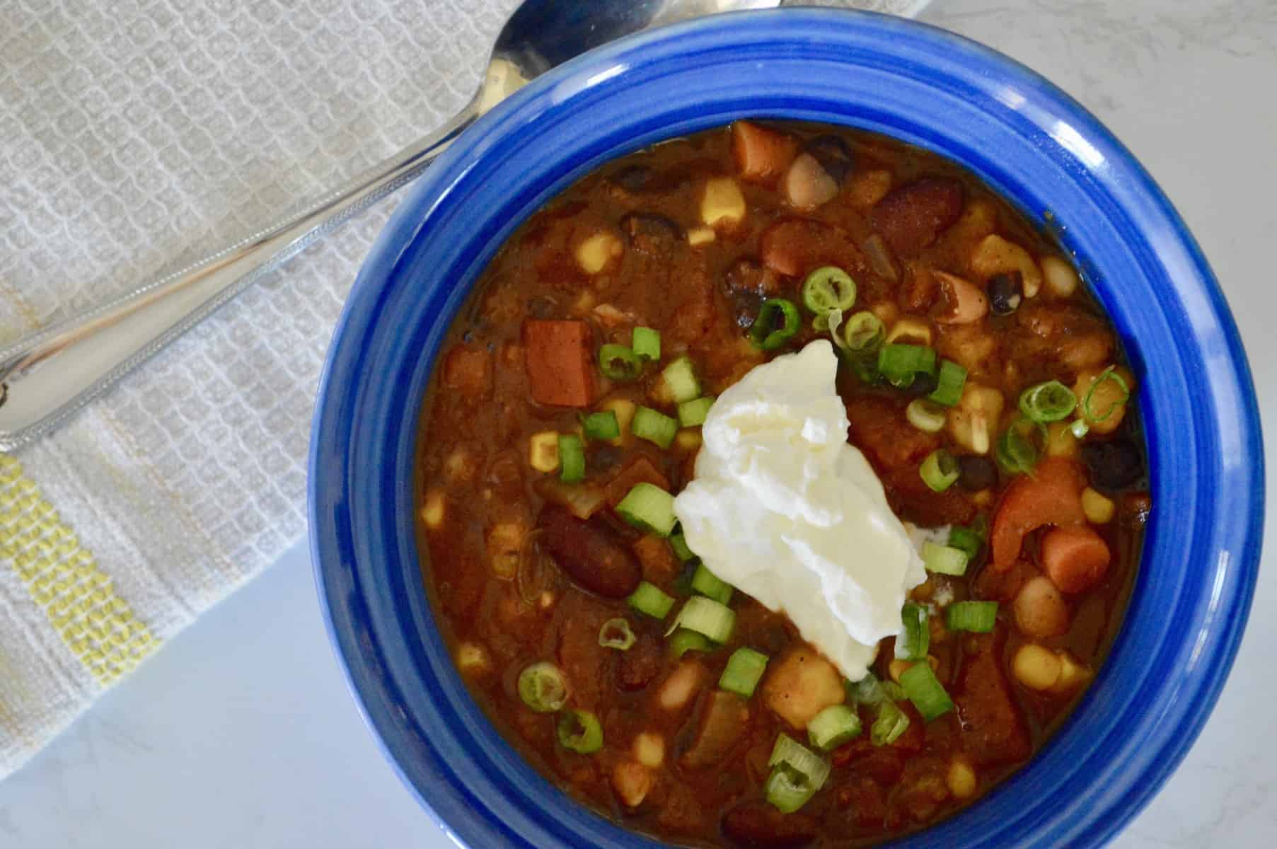 vegetarian chili in a blue bowl with sour cream on top
