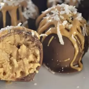 Peanut Butter Coconut Truffles on a white plate with a bite taken out of one