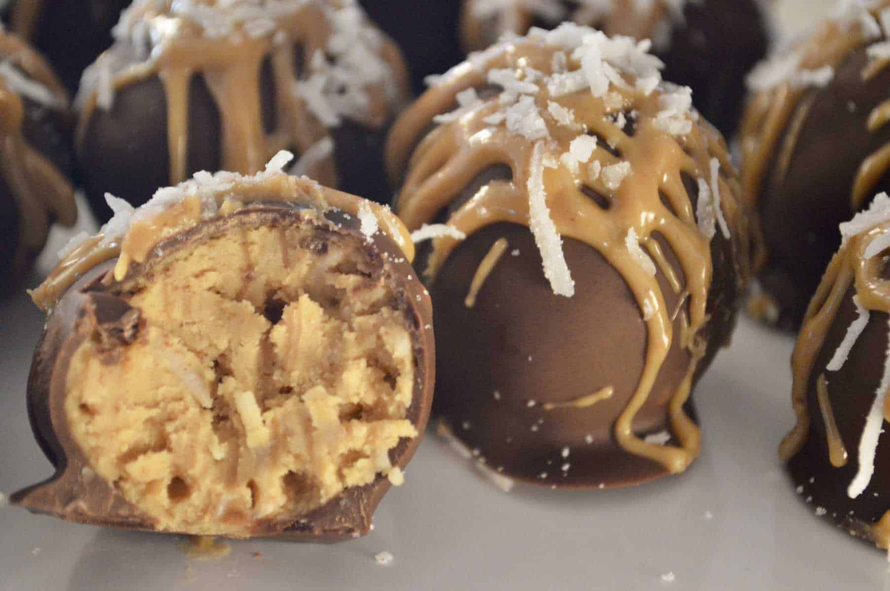 Peanut Butter Coconut Truffles on a white plate with a bite taken out of one