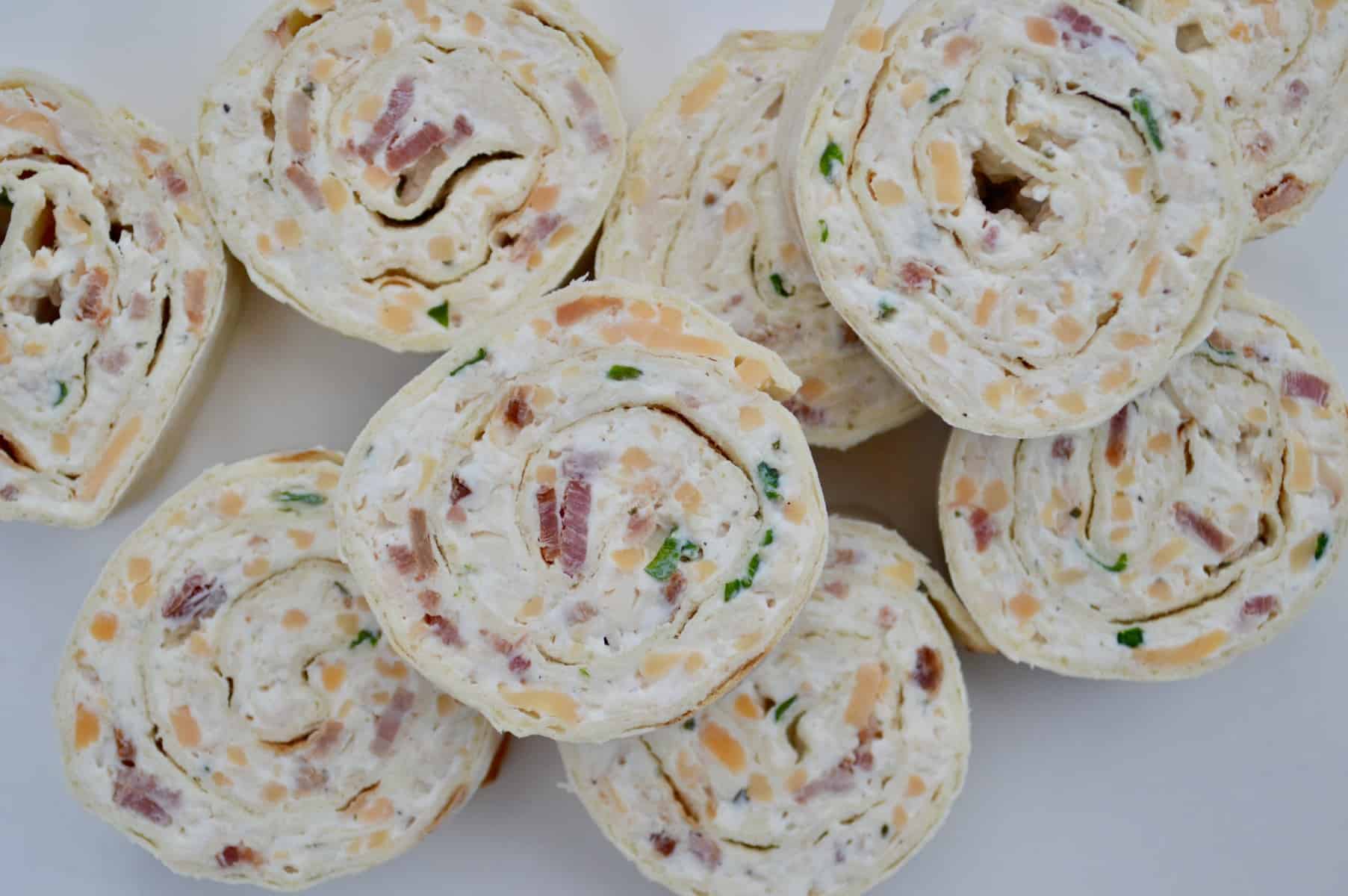 The ultimate make-ahead party appetizer, Chicken Bacon Ranch Pinwheels are super easy to make and such a crowd pleaser. Rotisserie chicken, cream cheese, bacon, cheddar, and ranch seasoning all rolled into a flatbread or tortilla. 