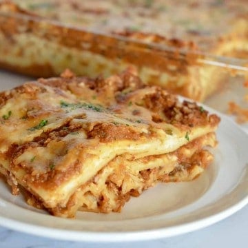 veggie lasagne on a white plate with a pan of it in the background