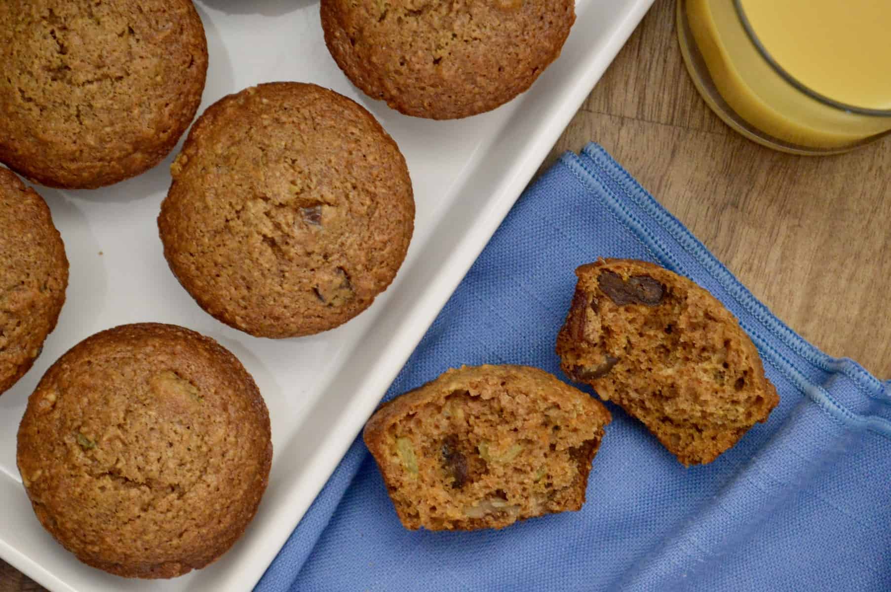 healthy carrot muffins on a white plate with a glass of orange juice on the side