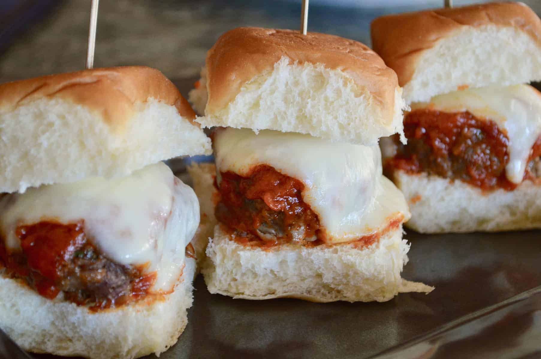 Easy Italian Meatball Sliders on a black plate with skewers in them