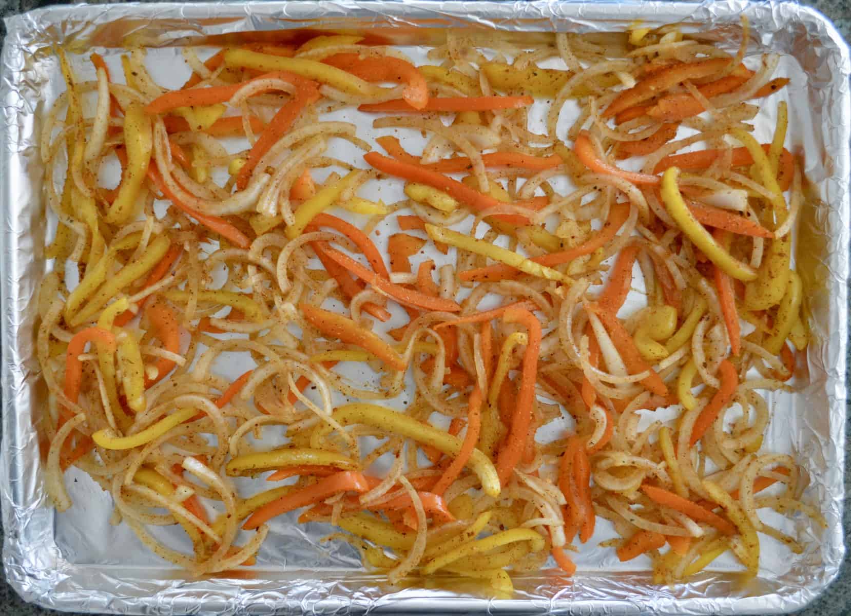 onions and bell peppers on a foil lined baking sheet 