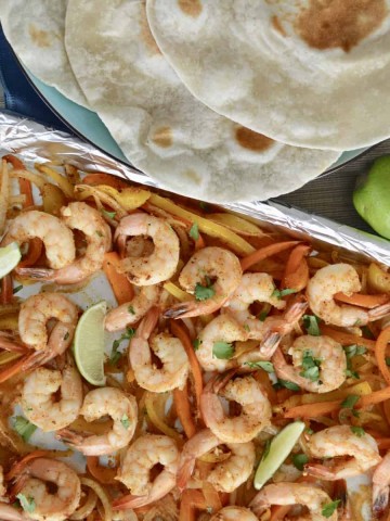 Sheet Pan Shrimp Fajita dinner set up with tortillas and lime
