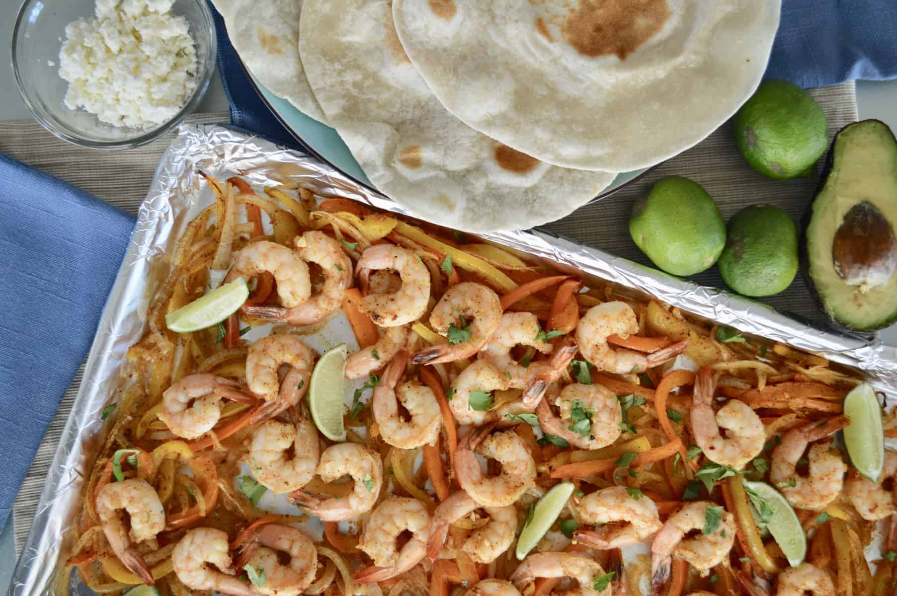 Sheet Pan Shrimp Fajita dinner set up with tortillas and lime