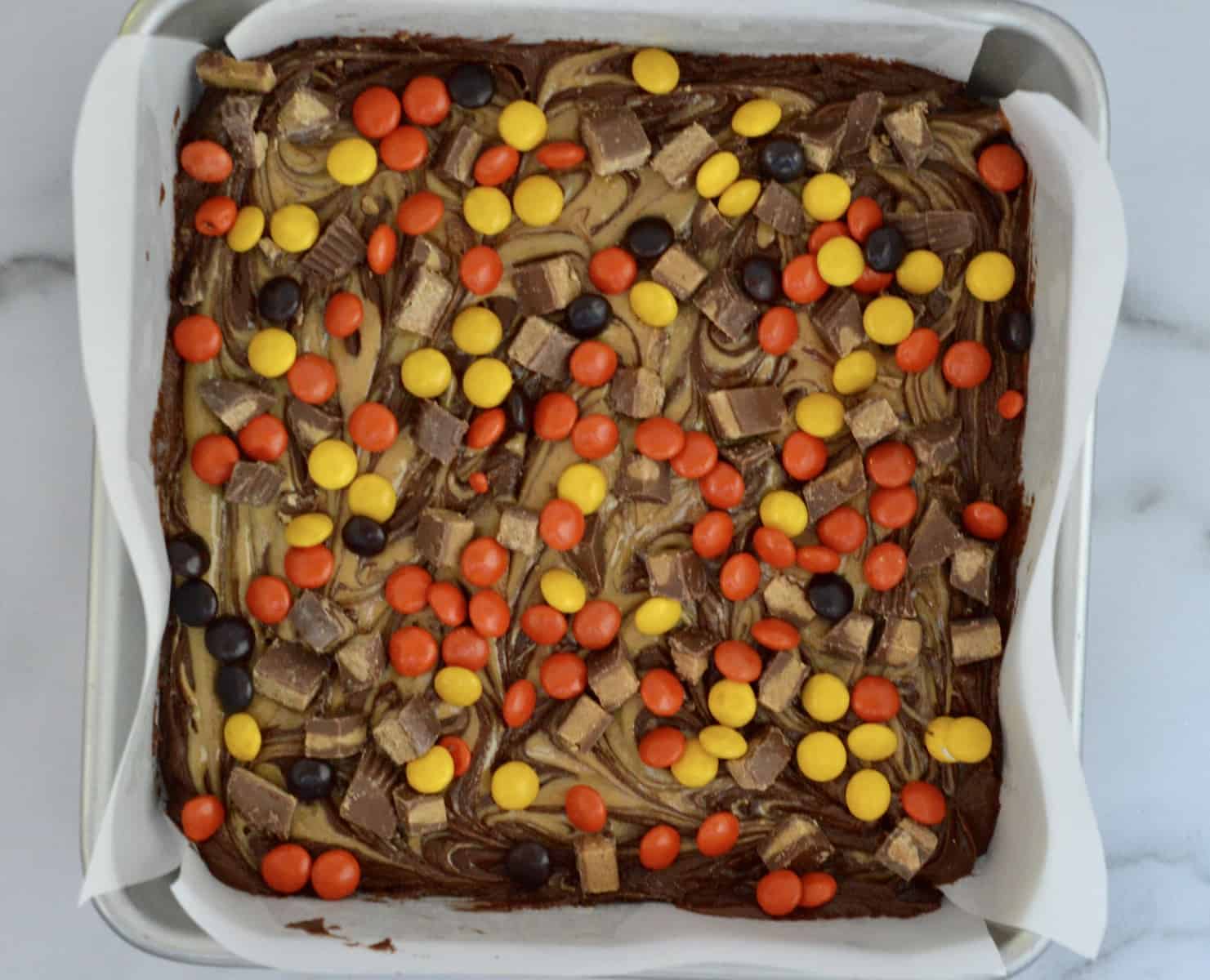sprinkle the peanut butter cups and Reese's pieces on the brownie peanut butter batter 
