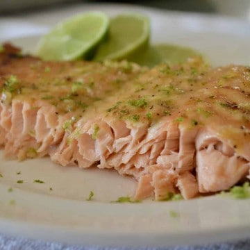 Honey lime Salmon on a white plate with lime slices